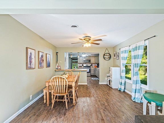 A dining room with a table and chairs and a ceiling fan.
