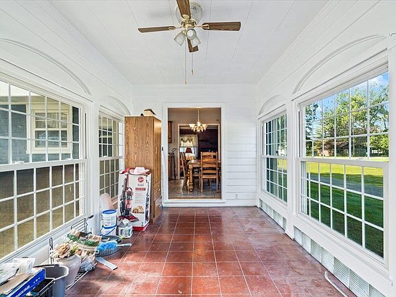 A porch with a lot of windows and a ceiling fan.
