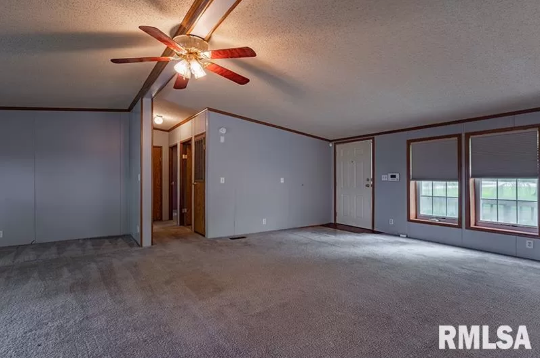 An empty living room with a ceiling fan and rmlsa written on the bottom