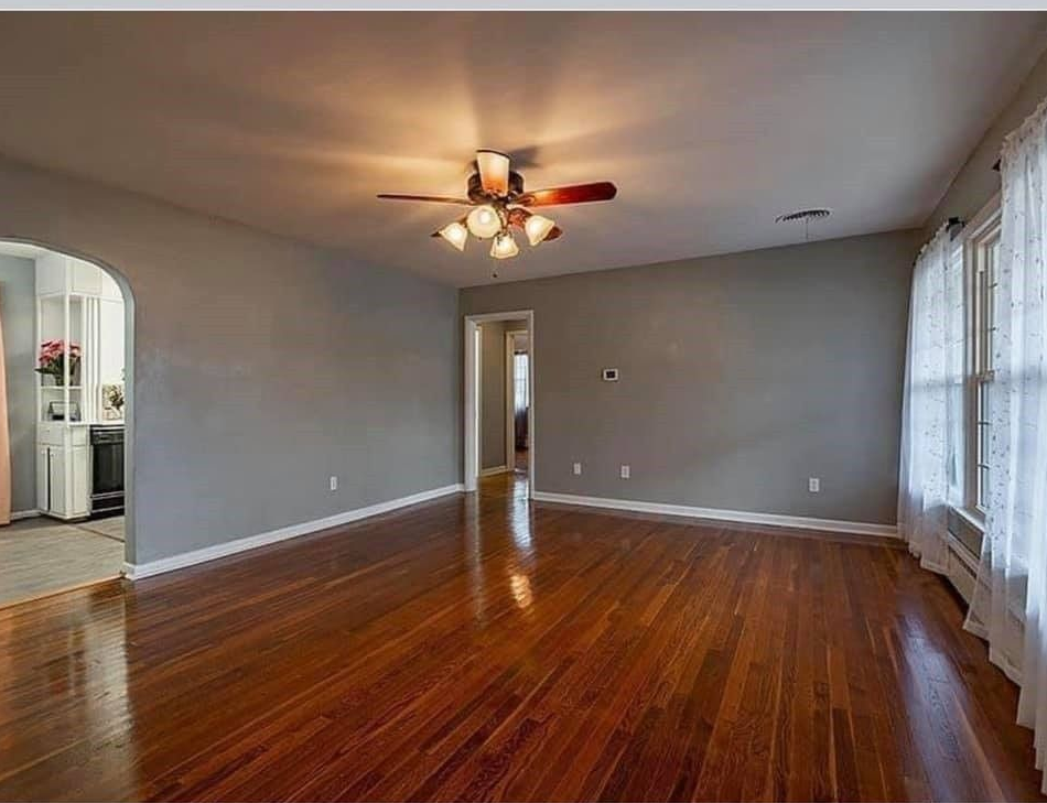 An empty living room with hardwood floors and a ceiling fan.