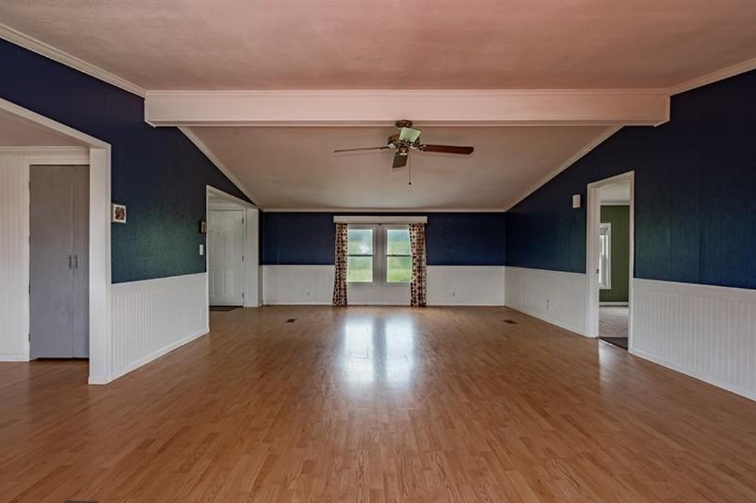A large empty room with hardwood floors and blue walls