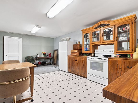 A kitchen with a stove , refrigerator , cabinets and a table.