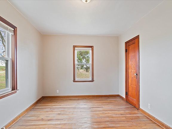 An empty room with hardwood floors and two windows.