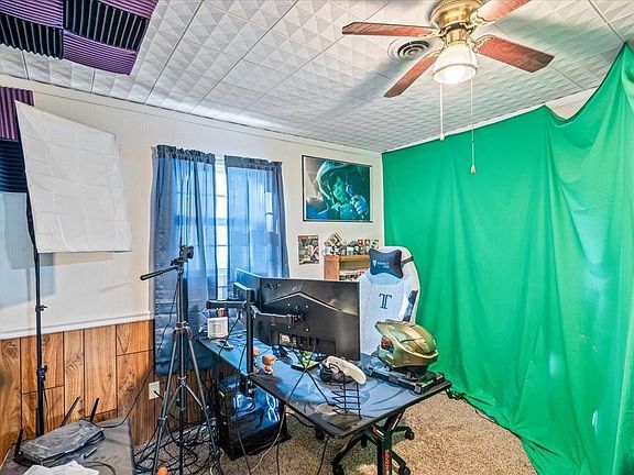 A room with a green screen and a ceiling fan.