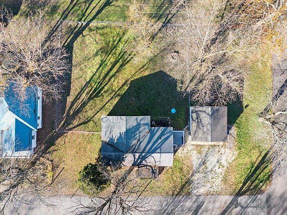 An aerial view of a house surrounded by trees and grass.
