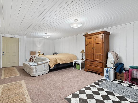 A bedroom with a bed , dresser , chair and checkered floor.
