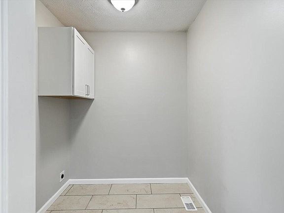 An empty room with a tiled floor and a ceiling light.
