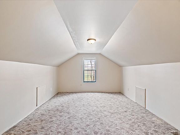 An empty attic with a vaulted ceiling and a window.