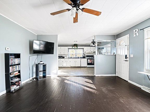 A living room with a ceiling fan and a flat screen tv.