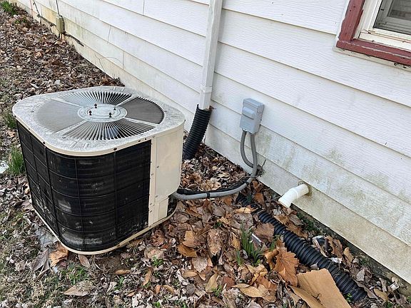 An air conditioner is sitting on the side of a house.