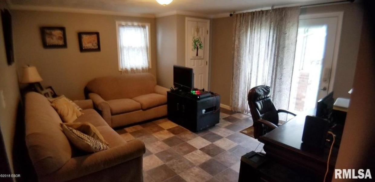 A living room with a couch , desk and television.