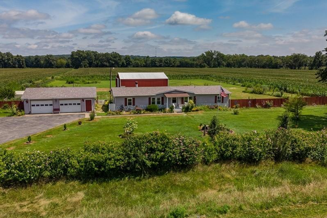 An aerial view of a house in the middle of a grassy field.