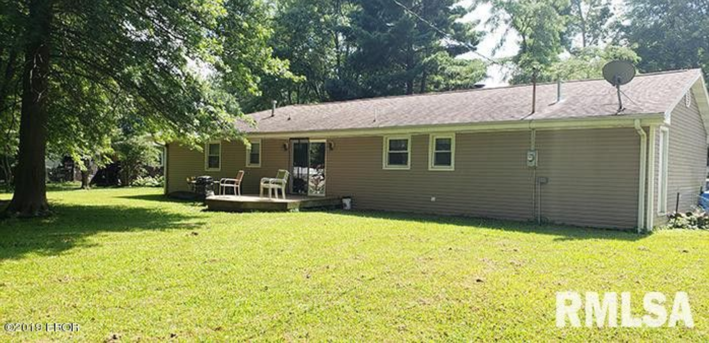 A house with a lot of grass and trees in front of it.