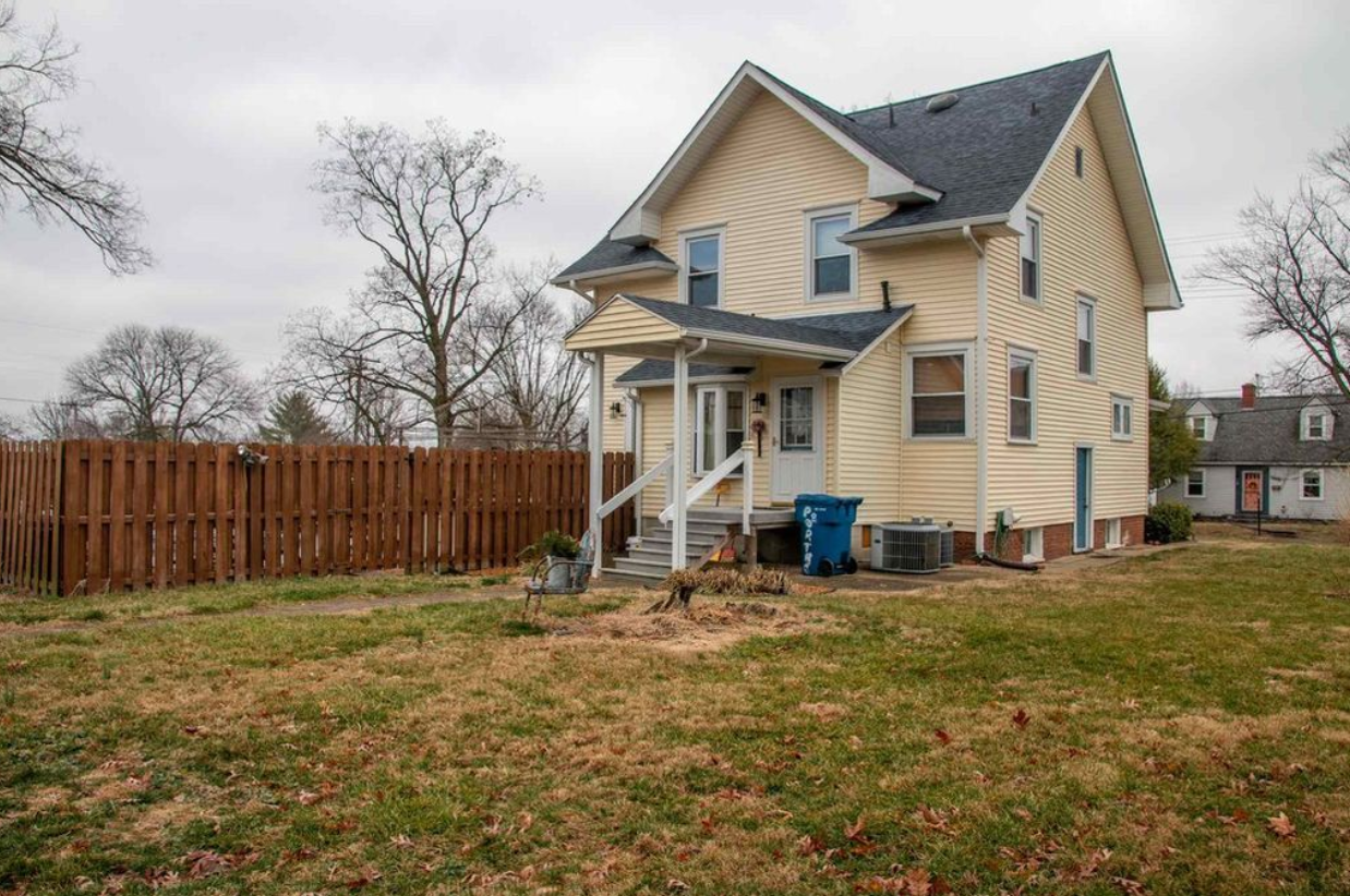 A large yellow house with a wooden fence in front of it.