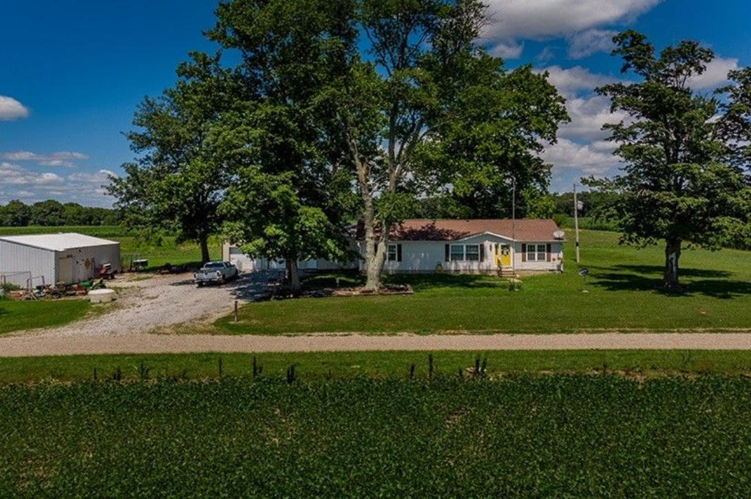An aerial view of a house in the middle of a grassy field.