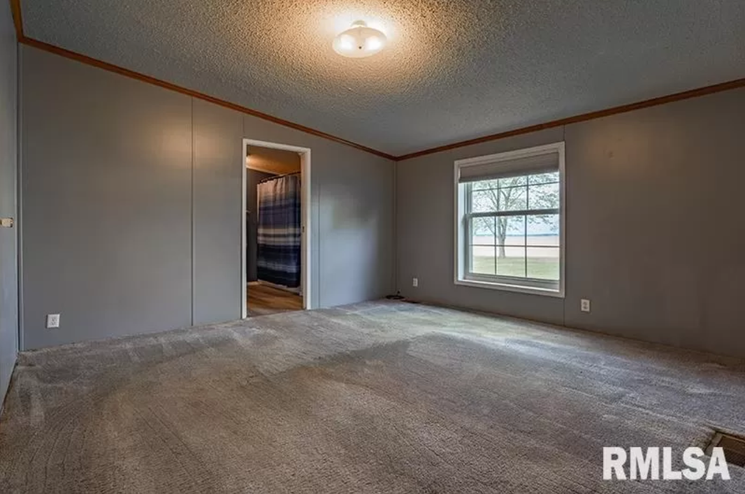 A large empty room with a carpeted floor and a window.