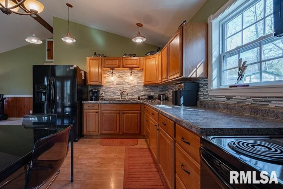 A kitchen with wooden cabinets and a black refrigerator