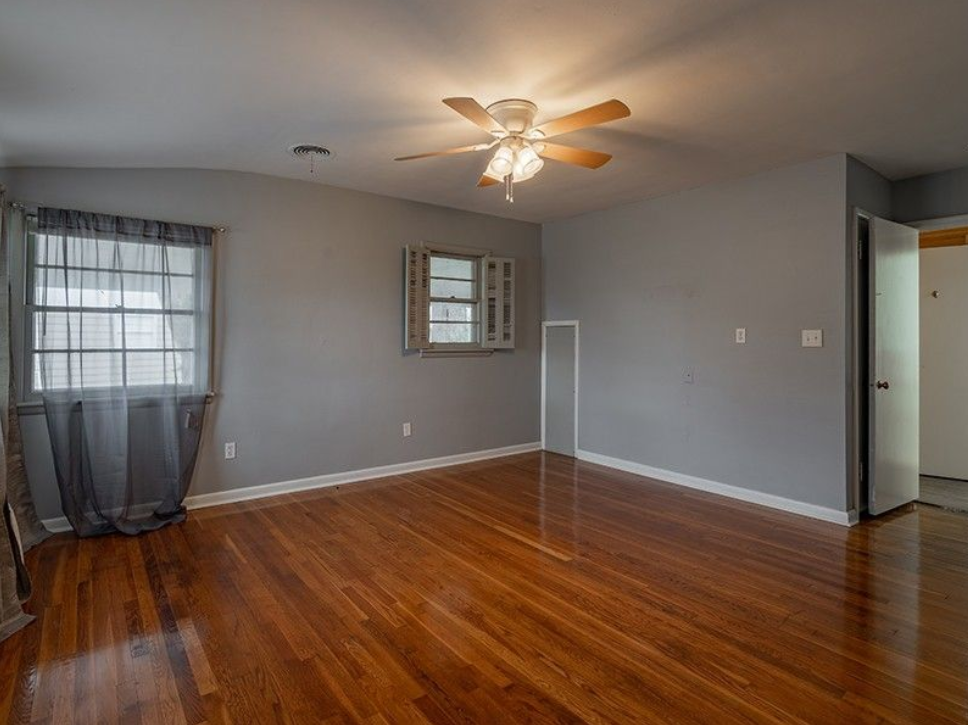 An empty living room with hardwood floors and a ceiling fan.