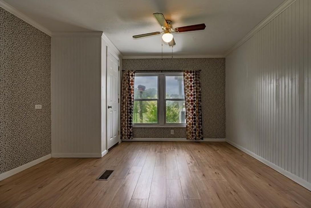 An empty room with hardwood floors and a ceiling fan.
