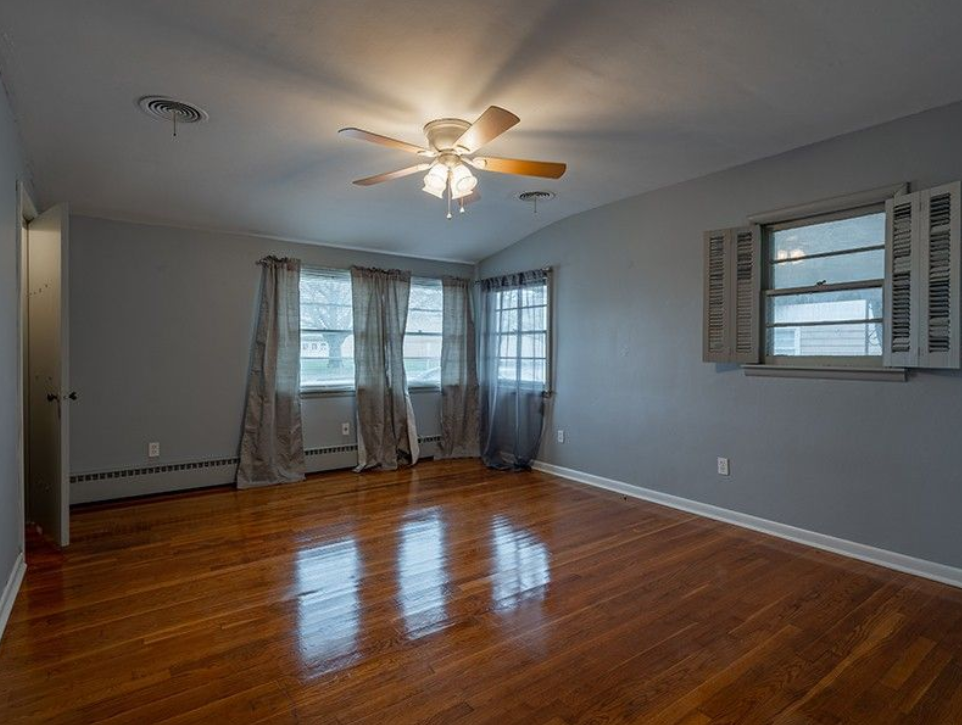 An empty room with hardwood floors and a ceiling fan.