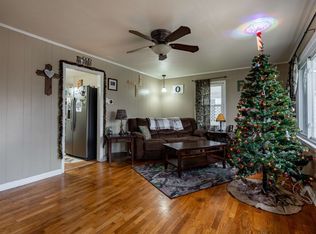 There is a christmas tree in the middle of the living room.