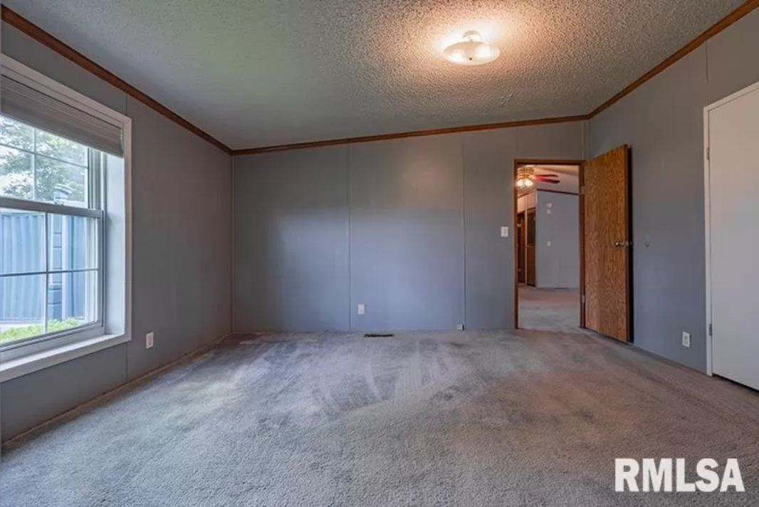 An empty room with a carpeted floor and a window.
