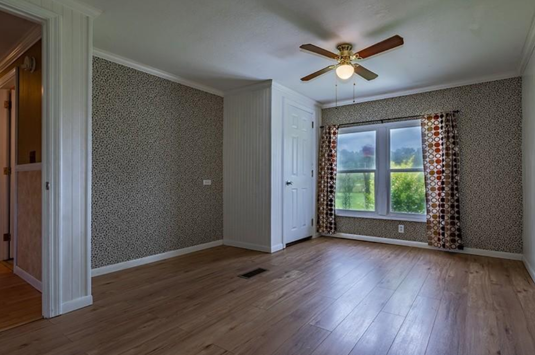 An empty room with hardwood floors and a ceiling fan.