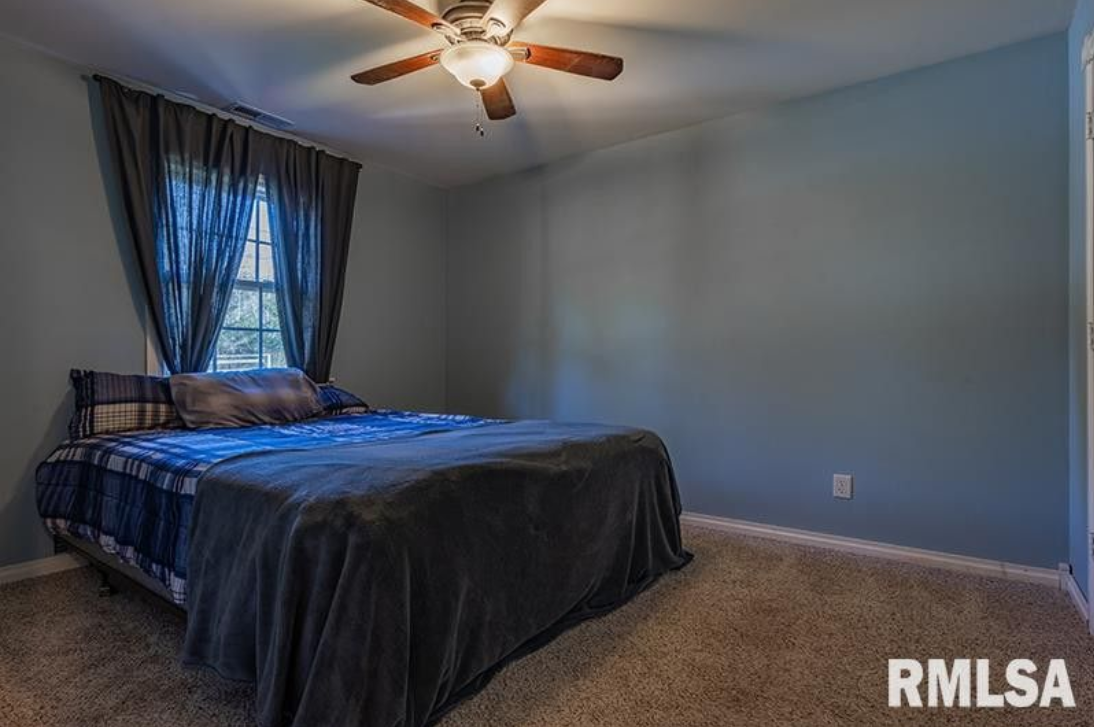 A bedroom with a large bed and a ceiling fan.