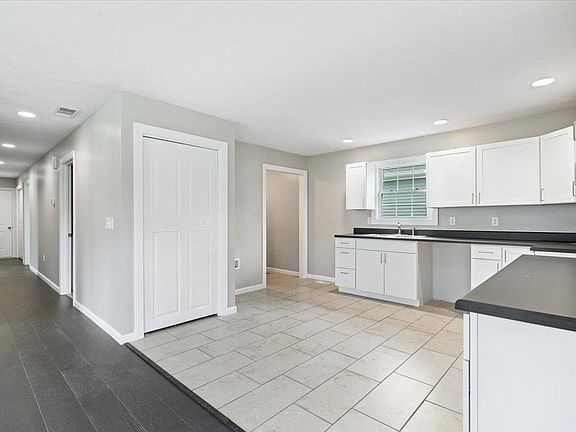 A kitchen with white cabinets and a black counter top.