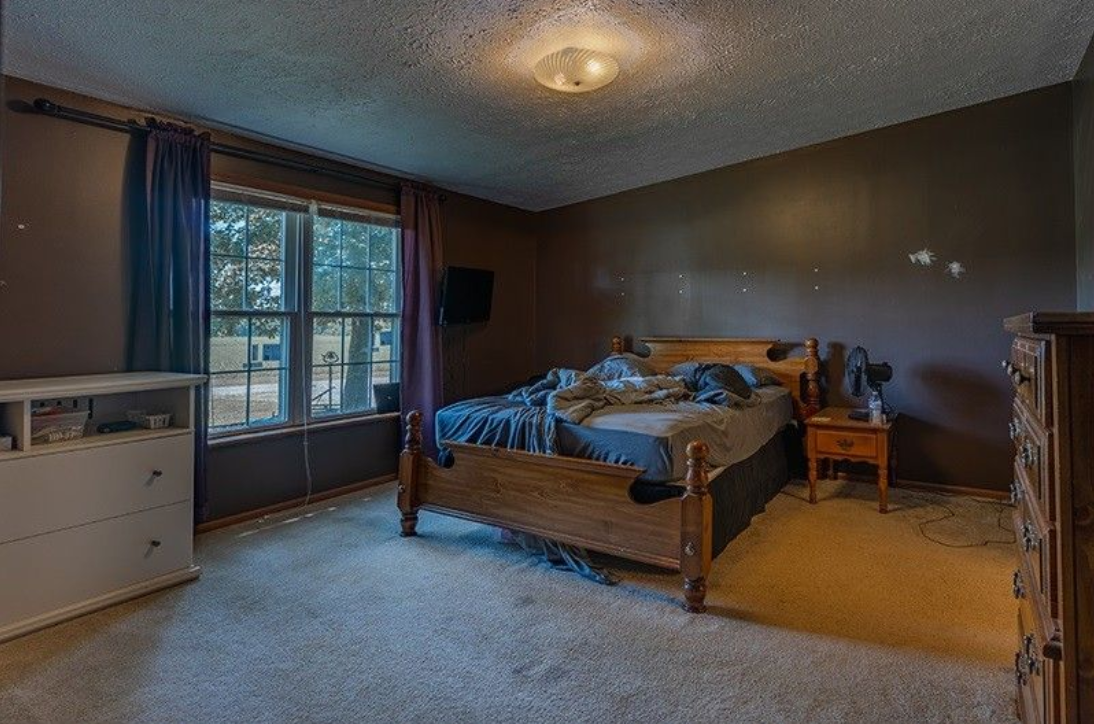 A bedroom with a bed , dresser , nightstand and window.