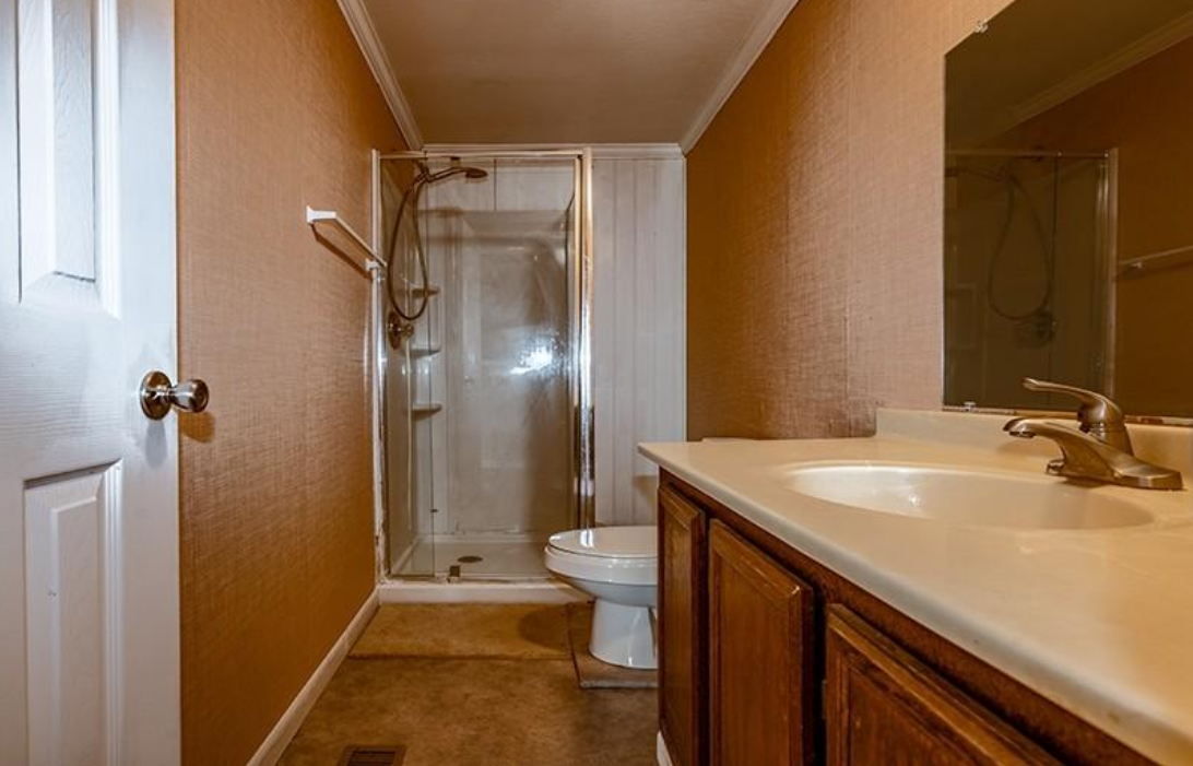 A bathroom with a sink , toilet , shower and mirror.