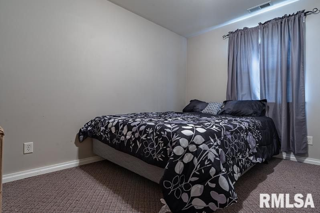 A bedroom with a bed , curtains and a window.