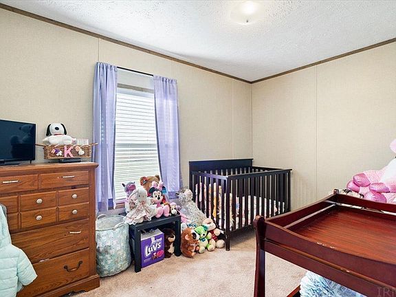 A bedroom with a crib , dresser , and television.