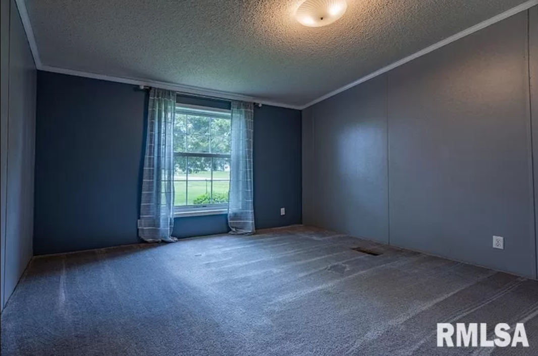 An empty room with a carpeted floor and a window.