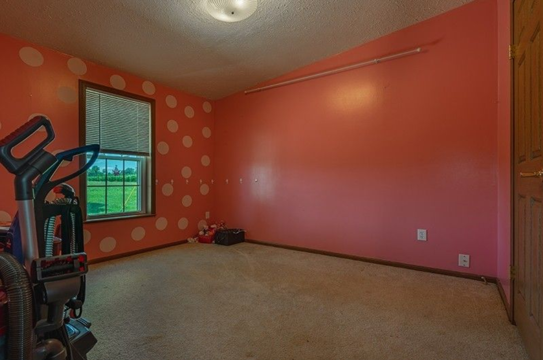 An empty room with pink walls and a window.