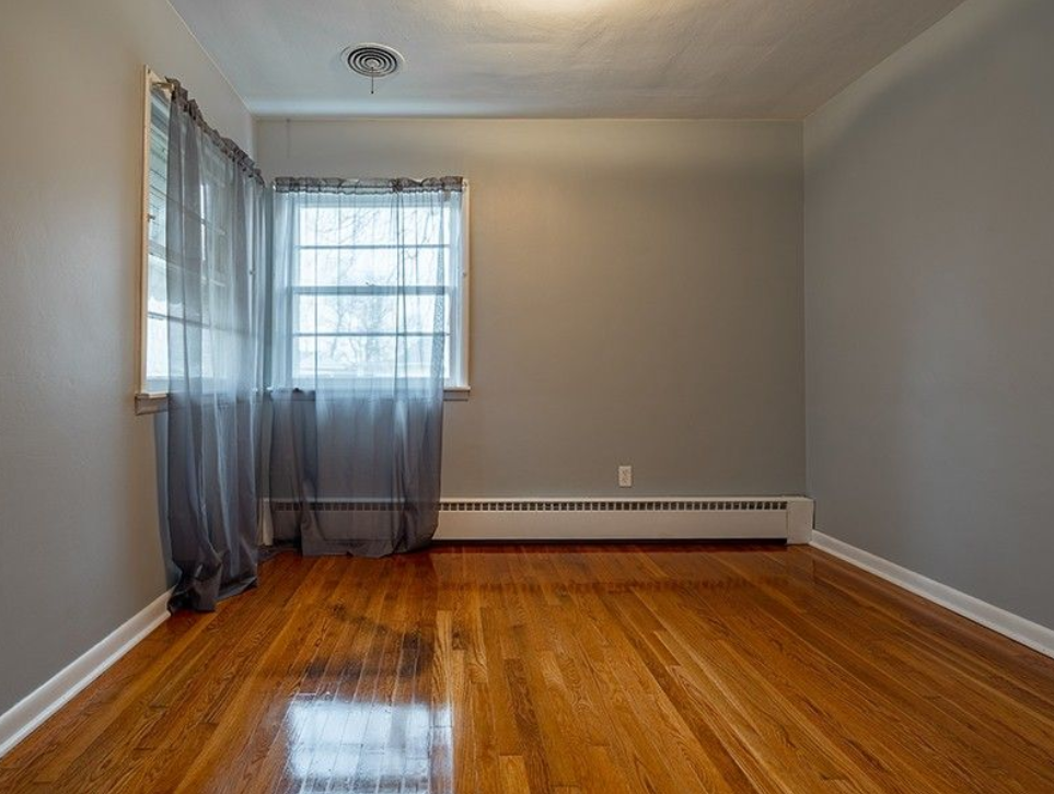 An empty living room with hardwood floors and a window.