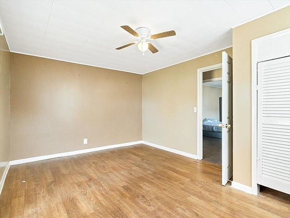 An empty bedroom with hardwood floors and a ceiling fan.