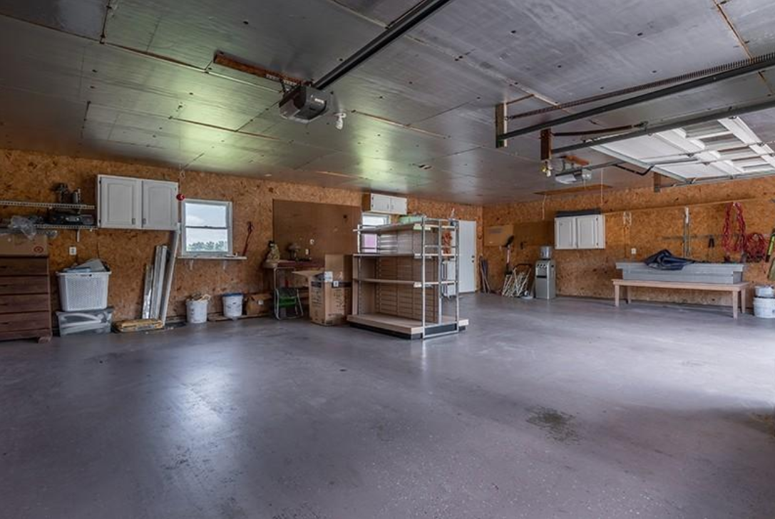 An empty garage with a garage door open and a lot of storage space.