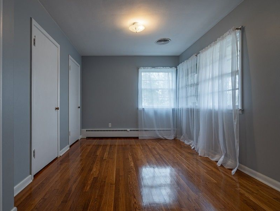 A hallway with hardwood floors and white curtains