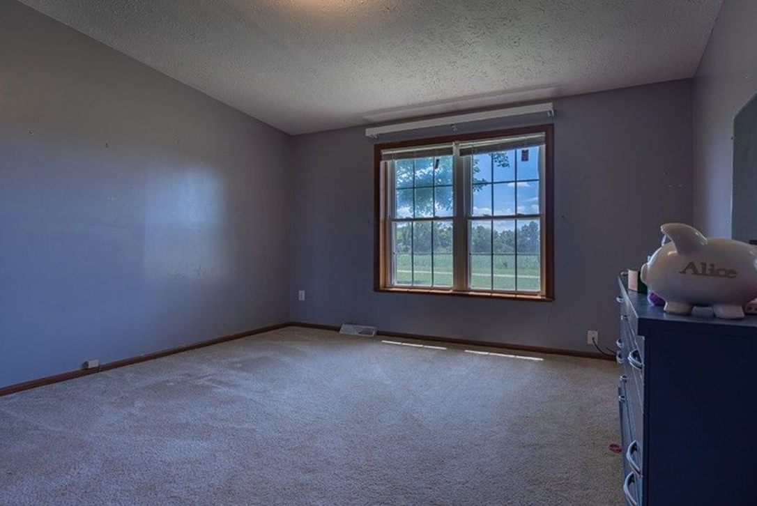 An empty bedroom with a piggy bank on top of a dresser.