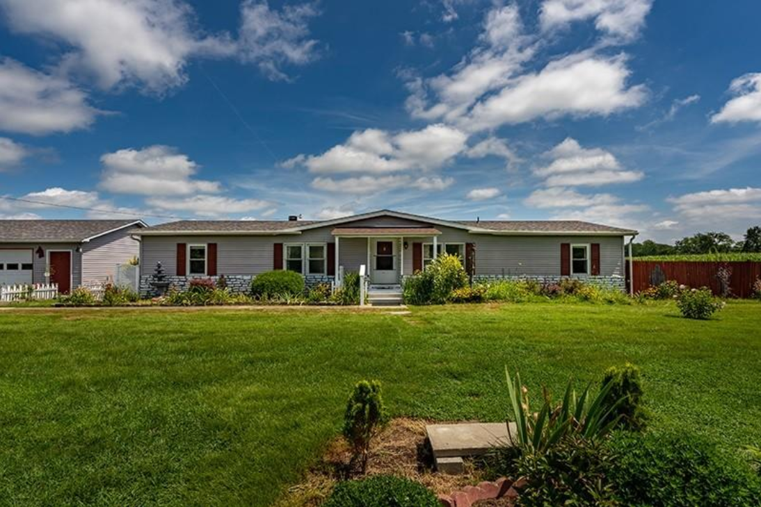 A mobile home is sitting on top of a lush green field.