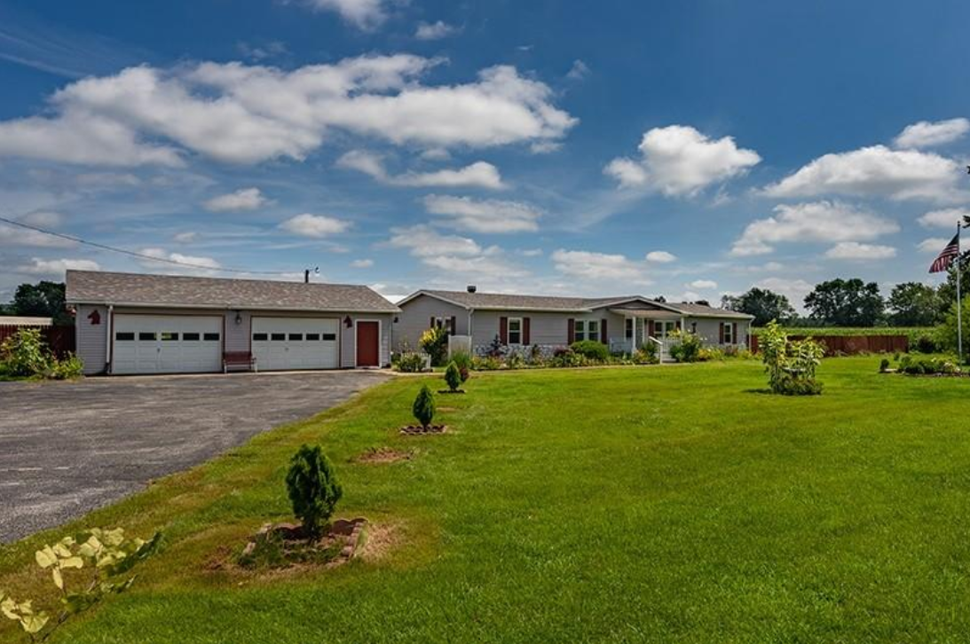A house with two garages and a large lawn in front of it.