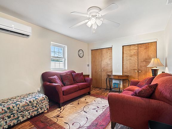 A living room with a couch , chair , ottoman and ceiling fan.