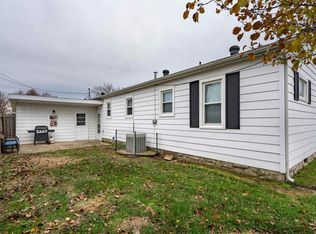 A white house with black shutters is sitting on top of a lush green field.