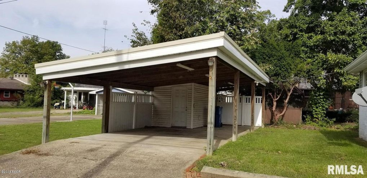 There is a carport in the backyard of a house.