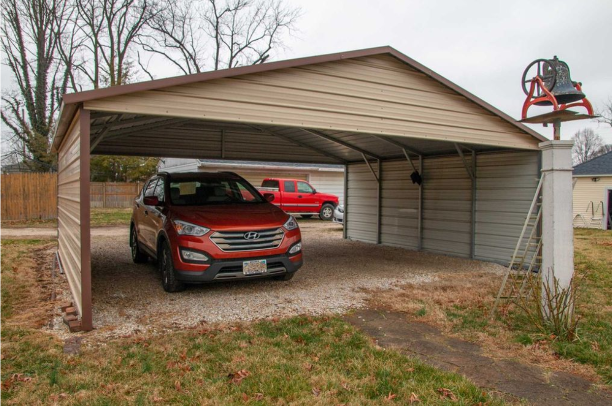 A red car is parked under a carport.