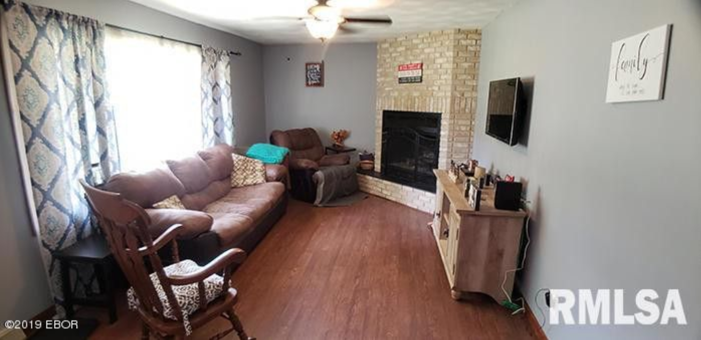 A living room with a couch , chair , fireplace and television.