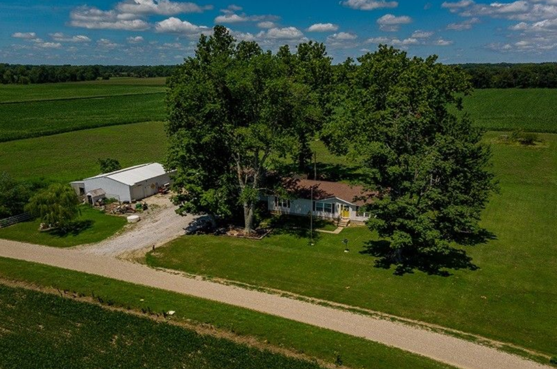 An aerial view of a house in the middle of a grassy field.