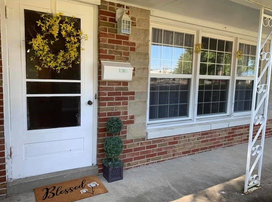 The front door of a brick house with a white door and a welcome mat.