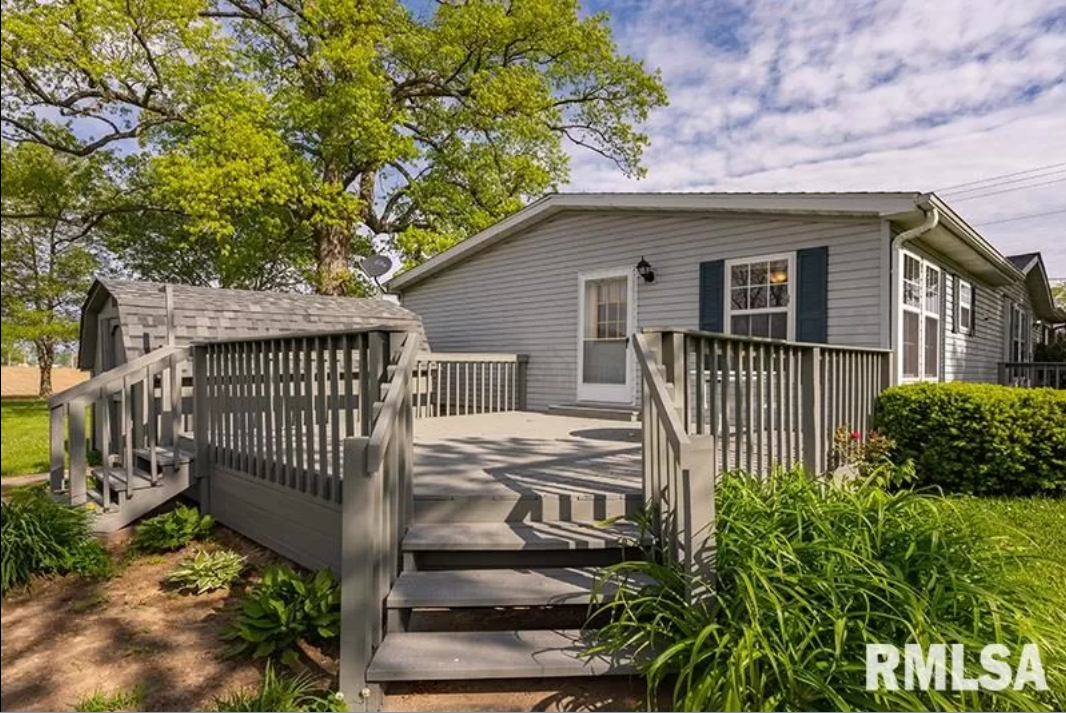 A mobile home with a large deck and stairs leading up to it.
